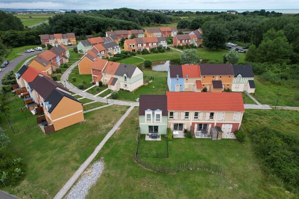 An aerial view of a residential area with colorful houses, a small pond, and a road. - Cottage du Phare, 3 bedrooms & garden, rated 3 stars (Cayeux-sur-Mer)