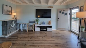 Ein Zimmer mit Holzboden, einem Schreibtisch mit Fernseher, einem Sessel, einer Lampe und einer Tür mit einer Nummer.