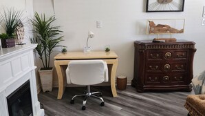 A room with a wooden desk, a white chair, a fireplace, a dresser, and a television mounted on the wall. - PRIVATE OASIS-MONTHLY RENTAL/ POOL/SPA/GOLF/WIFI/PARKING/REVIEWS! (Las Vegas)