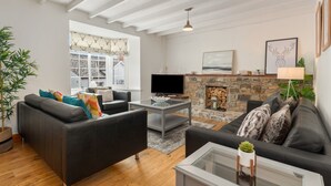 Ein modernes Wohnzimmer mit zwei schwarzen Sofas, einem Glastisch, einem Steinkamin und einem Fernseher.