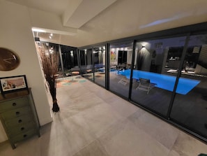 A modern interior with a glass wall leading to an outdoor pool area. - VILLA BEL AIR CANNES - NEW - Pool - No Party allowed - No bachelor-ette stay (Le Cannet)