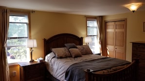 Une chambre à coucher avec un lit en bois, deux tables de chevet avec des lampes, une table de nuit et une fenêtre avec des rideaux.