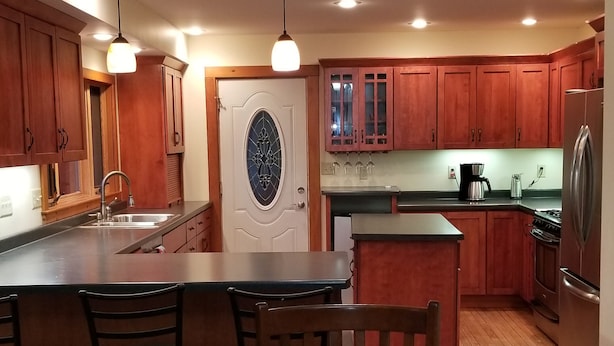 Une cuisine moderne avec des meubles en bois, un îlot central et un coin repas comprenant une table et des chaises.