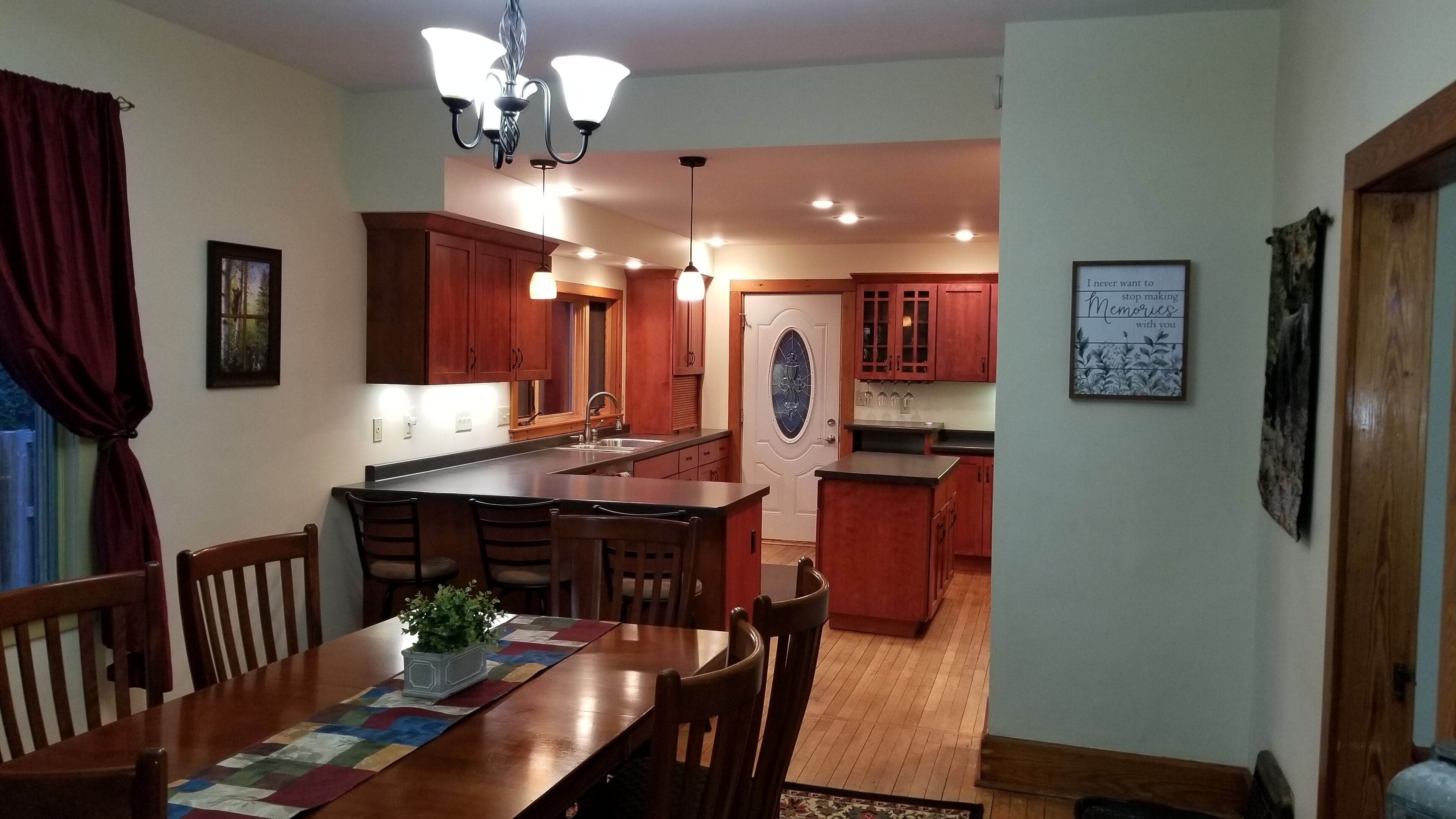 A spacious kitchen with wooden cabinets, a central island, and pendant lighting.