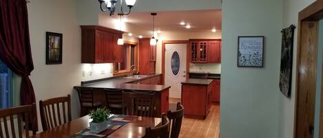 A spacious kitchen with wooden cabinets, a central island, and pendant lighting.
