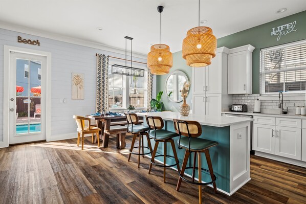 A modern kitchen with white cabinets, a teal island, and wooden flooring.