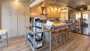 A modern kitchen with stainless steel appliances, wooden flooring, and a bar area with stools. - Welcome to Forest Lakehouse at Lake Cumberland – Your Ideal Cabin Retreat! (Burnside)