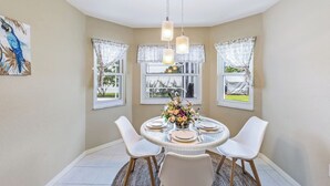 Un coin repas avec une table ronde, des chaises blanches et une composition florale en guise de centre de table.