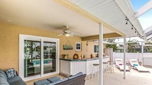 Un patio abrité avec une piscine, un bar et des chaises longues.