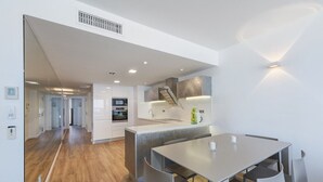 Une cuisine moderne dotée d’un îlot central, d’un coin repas avec deux chaises et d’un escalier menant à un autre niveau.