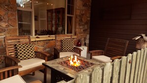 An outdoor seating area with stone walls, wooden chairs, and a fire pit. - Spacious, custom home, large fenced yard. Fast fiber internet! STR-1-2024-057 (RIDGWAY)