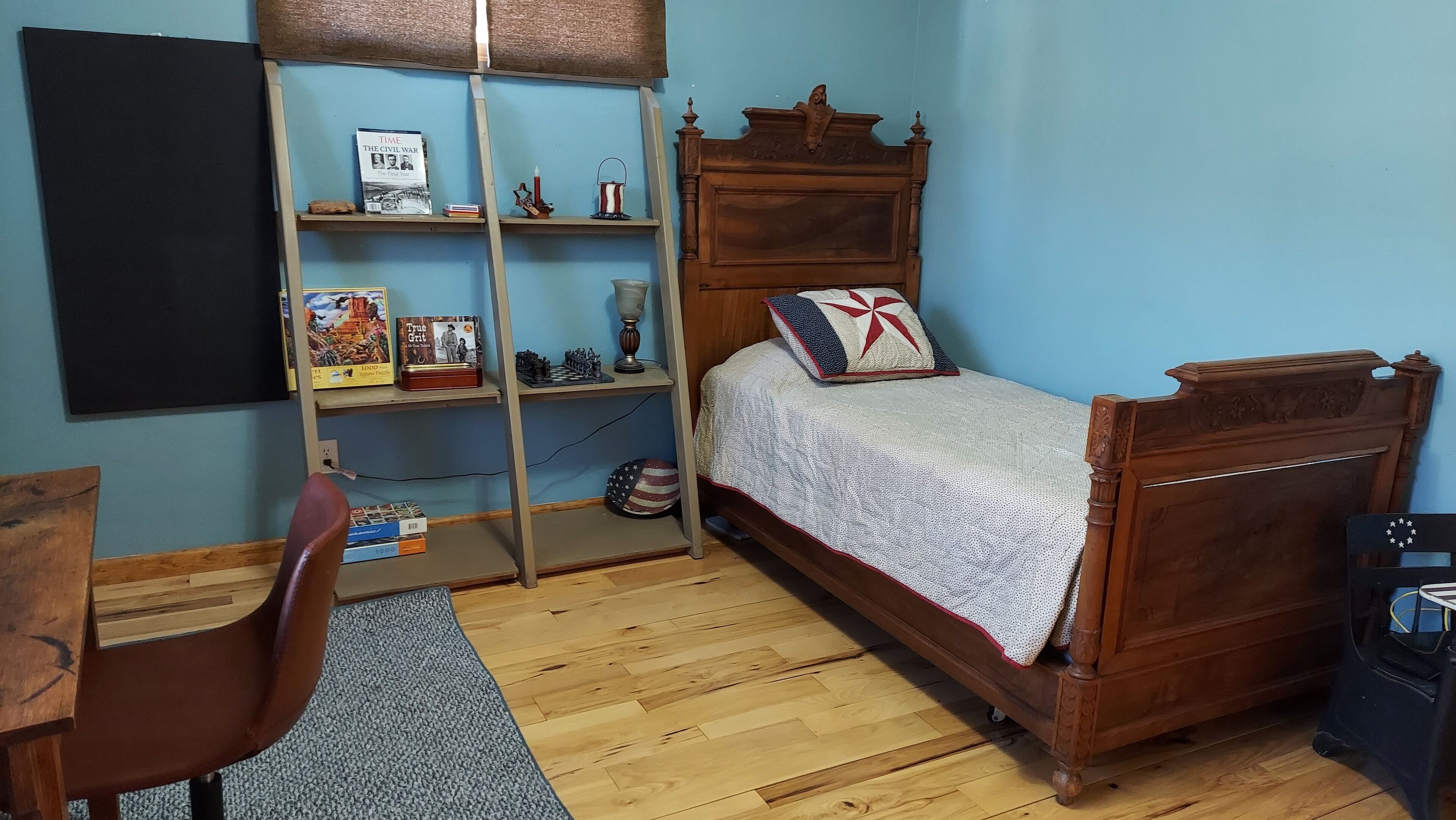 Een slaapkamer met een houten bed, een bureau en een boekenkast.