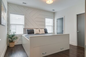 Relax in this serene bedroom with a bed, storage drawers, and a geometric-patterned ceiling.