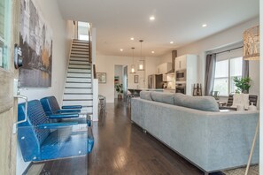 Relax in this stylish living area with a comfortable sofa, a wooden staircase, and a cityscape artwork.