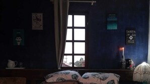 Makuuhuoneessa on sänky, ikkuna, yöpöytä ja seinä, jossa on kyltti.