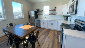 Une cuisine moderne avec des meubles blancs, des appareils en acier inoxydable et une table à manger en bois.