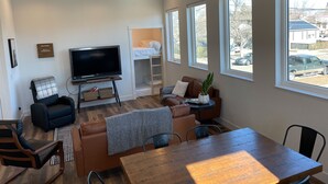 Un salon moderne avec un téléviseur, un canapé et un coin repas.