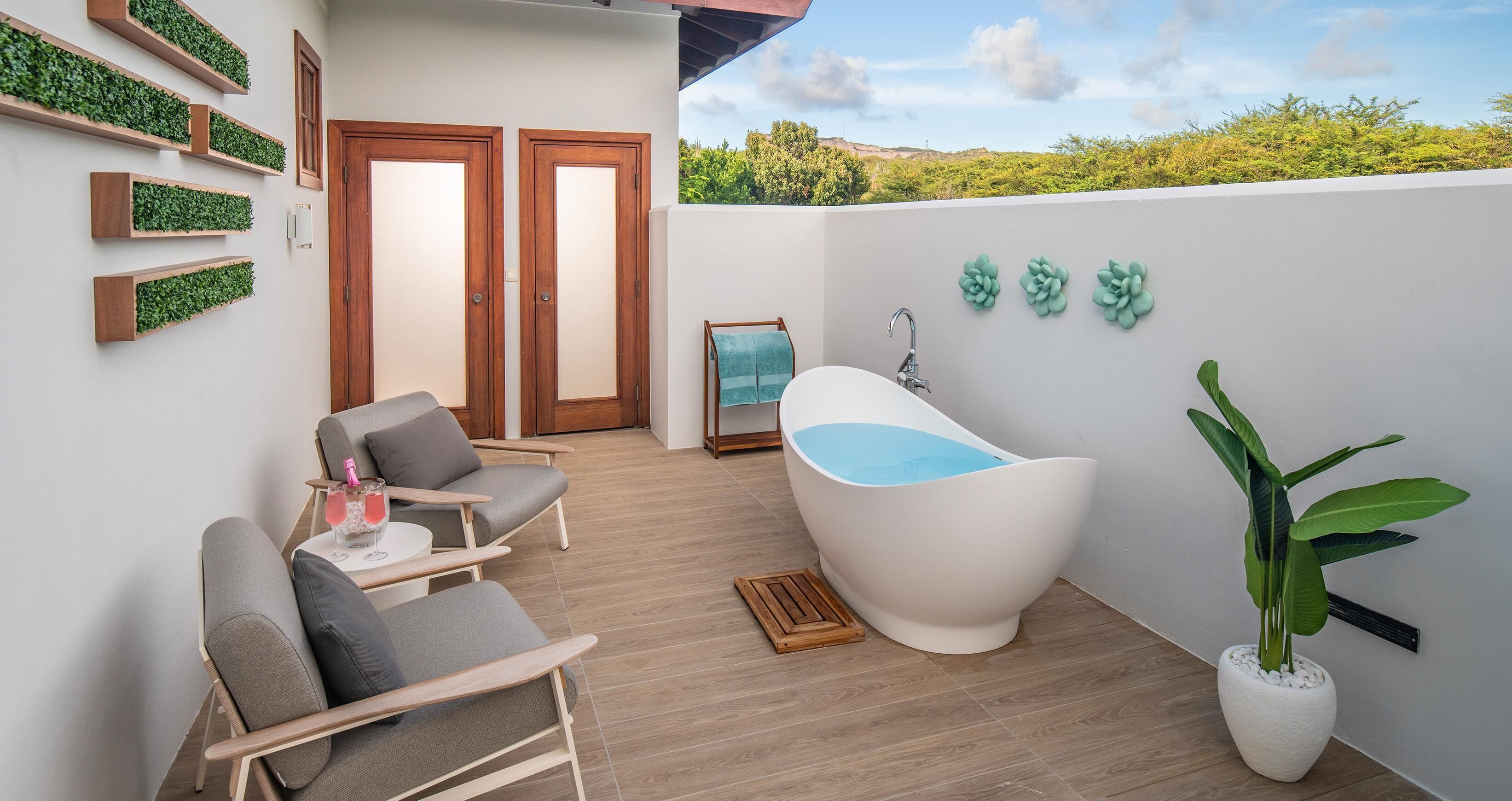 Un espacio al aire libre moderno con una bañera blanca, una planta en maceta y vistas al paisaje.