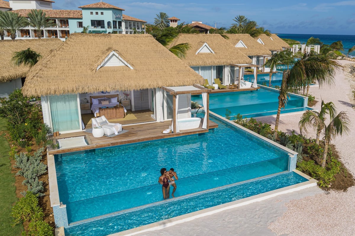 Ein Fernblick über den Ozean, ein überwasserbungalows und ein Strand mit einem Infinity-Pool.
