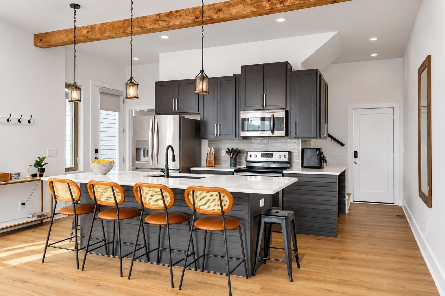 A modern kitchen with dark cabinets, stainless steel appliances, and a central island with bar stools.