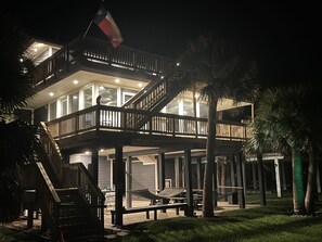 Una casa de dos pisos con balcón, palmeras y una bandera.