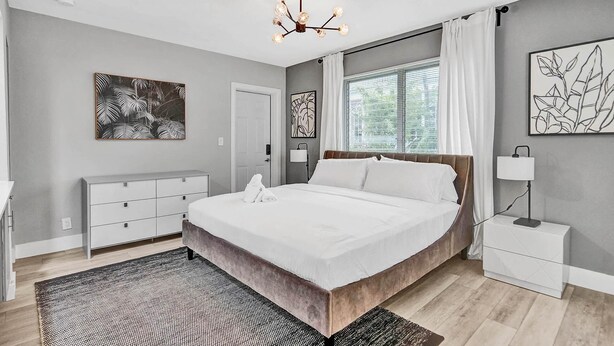A modern bedroom with a large bed, a nightstand, a dresser, and artwork on the walls. - Queens Suite 2BD/2BA Miami Beach Lincoln Casa (Miami Beach)