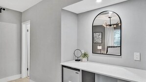 A modern bathroom with a white countertop, a built-in dishwasher, a mirror, and a ceiling light fixture. - Queens Suite 2BD/2BA Miami Beach Lincoln Casa (Miami Beach)