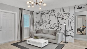 A modern living room with a grey sofa, a white coffee table, and a unique abstract wall art. - Queens Suite 2BD/2BA Miami Beach Lincoln Casa (Miami Beach)