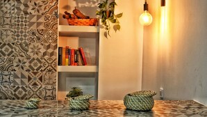 A room with patterned walls, a bookshelf with books, a hanging light bulb, and woven baskets on the floor.