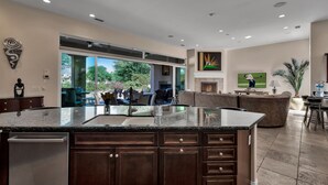 A modern kitchen with a large island, dark wood cabinets, and a view to the outdoor patio.