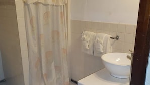 A bathroom with a white sink, a towel rack with two towels, and a shower curtain with a shell pattern.