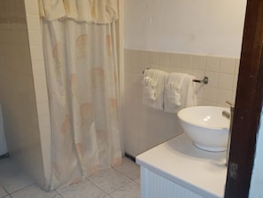 Bathroom features a shower curtain, sink, and towels.