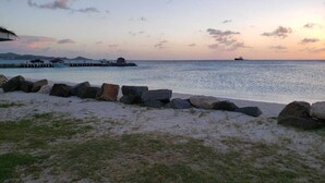 A beach with a rocky breakwater and a pier extending into the water.