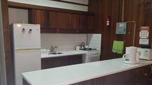 A kitchen with wooden cabinets, a white countertop, a refrigerator, a stove, and a coffee maker.