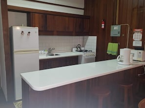 Compact kitchen with refrigerator, stove, and coffee maker.