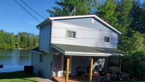 Ein zweistöckiges Haus mit überdachter Veranda, einer kleinen Terrasse und einer Garage.