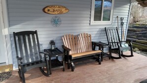 Eine Holzterrasse mit Adirondack-Stühlen, einer Holzbank und einem Schild mit der Aufschrift 'Blake's Cabin'.