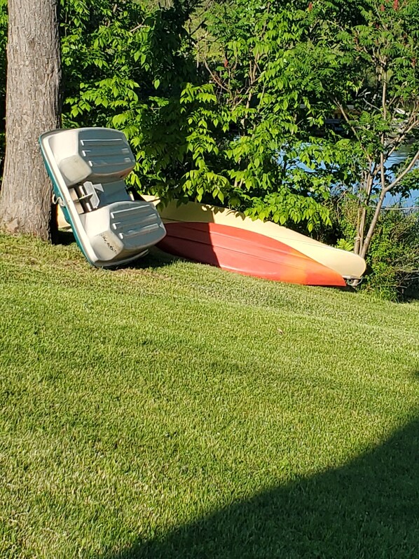 A boat lying on its side in a grassy area with trees in the background.