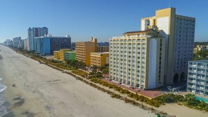 A coastal hotel with multiple buildings, a beach, and a pool area.