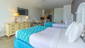 A hotel room with two beds, a desk, a chair, a television, and a kitchenette.