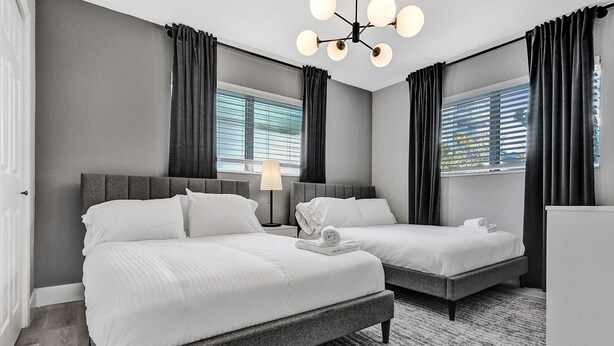A hotel room with two beds, a modern chandelier, and large windows with curtains. - Madison Suite 2 BD/2BA Miami Beach Lincoln Casa (Miami Beach)