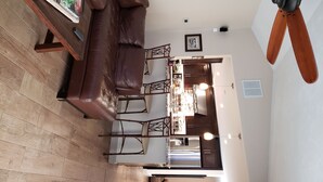 A modern living room with a brown leather sofa, wooden floor, and a ceiling fan.
