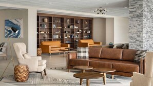 Un salon moderne avec des canapés en cuir, une bibliothèque en bois et un tapis à motifs.