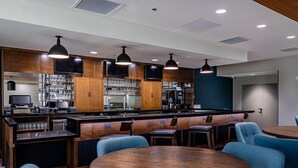 Un espace bar moderne avec des meubles en bois, des tabourets de bar et des luminaires suspendus.