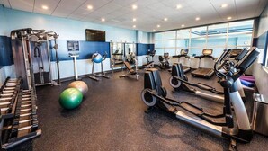 Une salle de sport équipée de tapis de course, de vélos elliptiques et de poids libres.