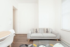 A modern living room with a sofa, a glass coffee table, and a white wall. - Stunning Sydney Home 1 (Millers Point)