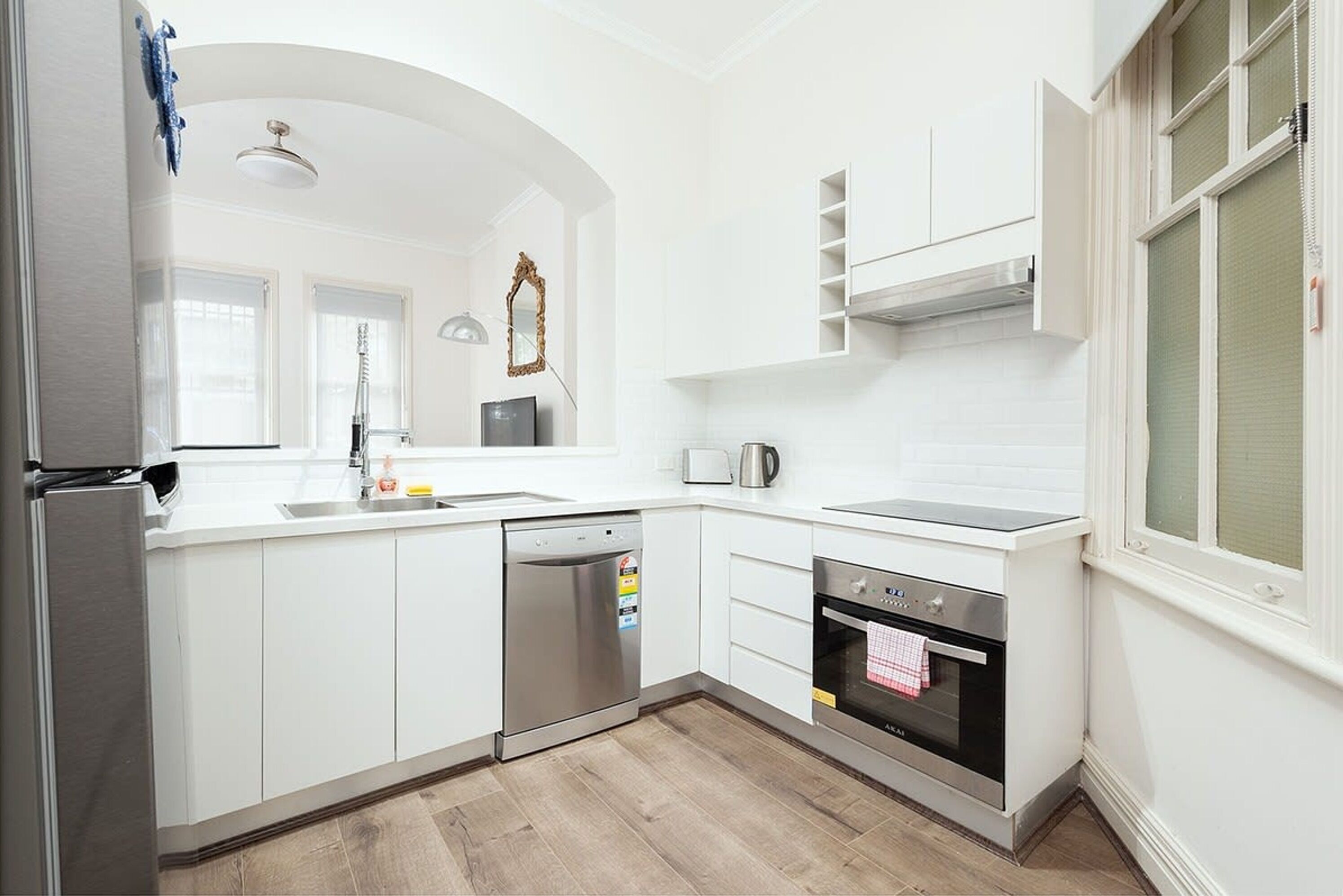 A modern kitchen with white cabinetry, a dishwasher, an oven, and a microwave.