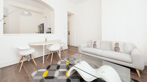 A modern living room with a white sofa, a glass coffee table, and a dining area with a white table and chairs. - Stunning Sydney Home 1 (Millers Point)