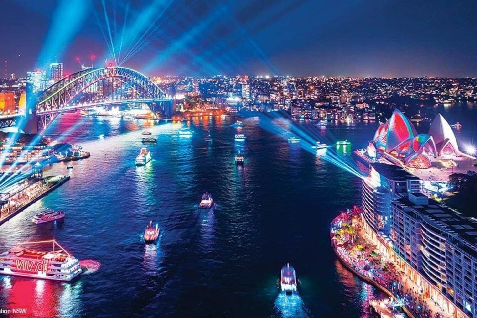A nighttime cityscape with a prominent bridge and a large opera house.