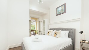 Ein Schlafzimmer mit einem großen Bett, einem Nachttisch mit Lampe und Blick ins Freie.